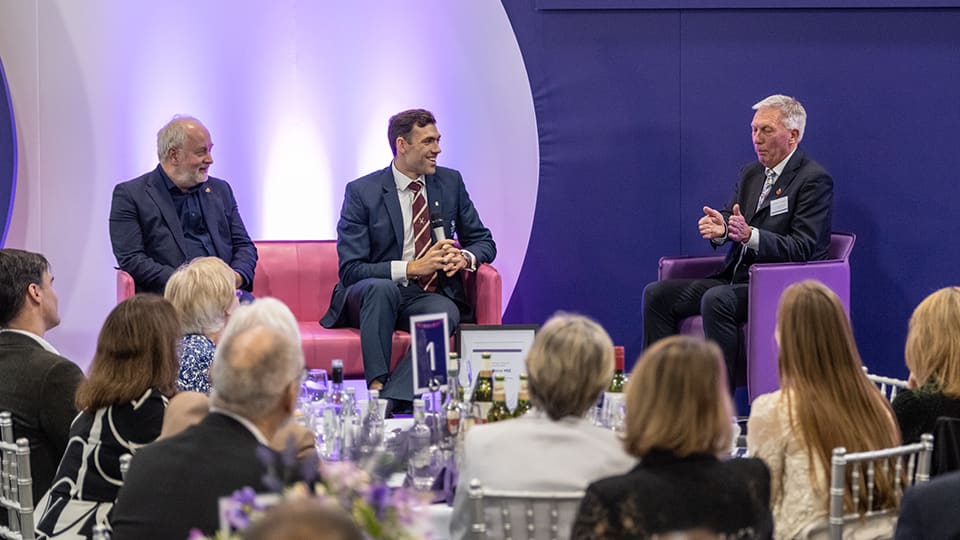 Matt Gotrel seated on stage with Professor Nick Jennings and David Moorcroft