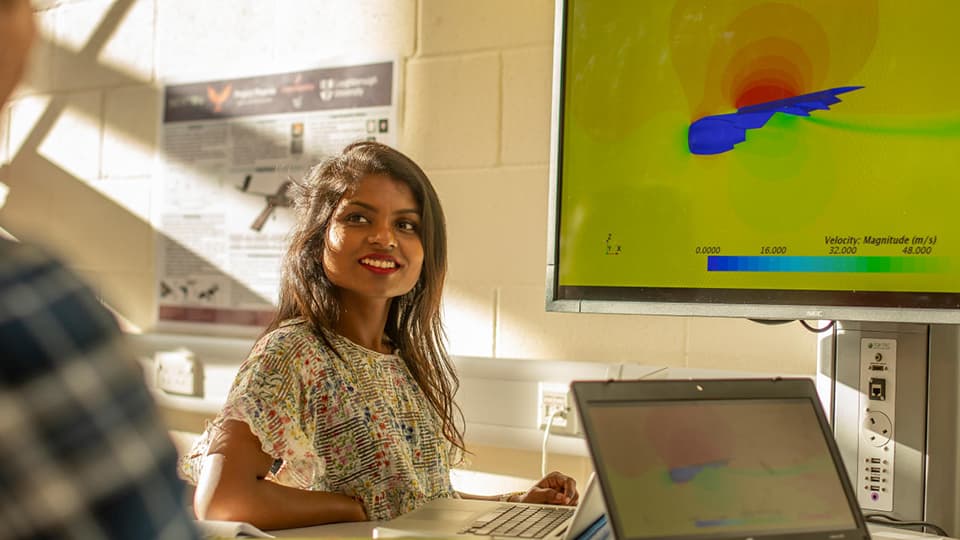 female student with laptop and screen smiling