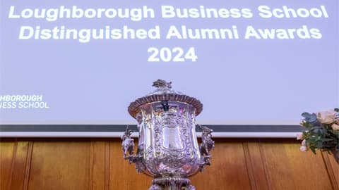 A trophy in front of a screen that reads 'Distinguished Alumni Awards 2024'.