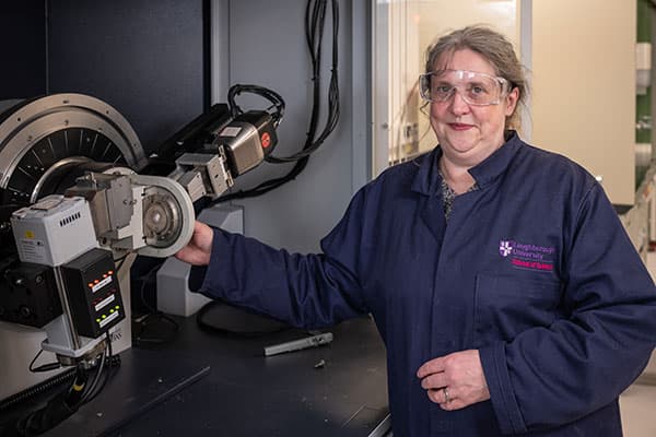 Sandie Dann beside a piece of laboratory equipment.