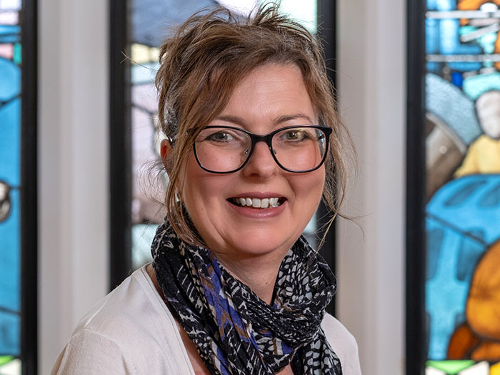 Portrait of Fleur Moss-Burdett against a stained glass window background