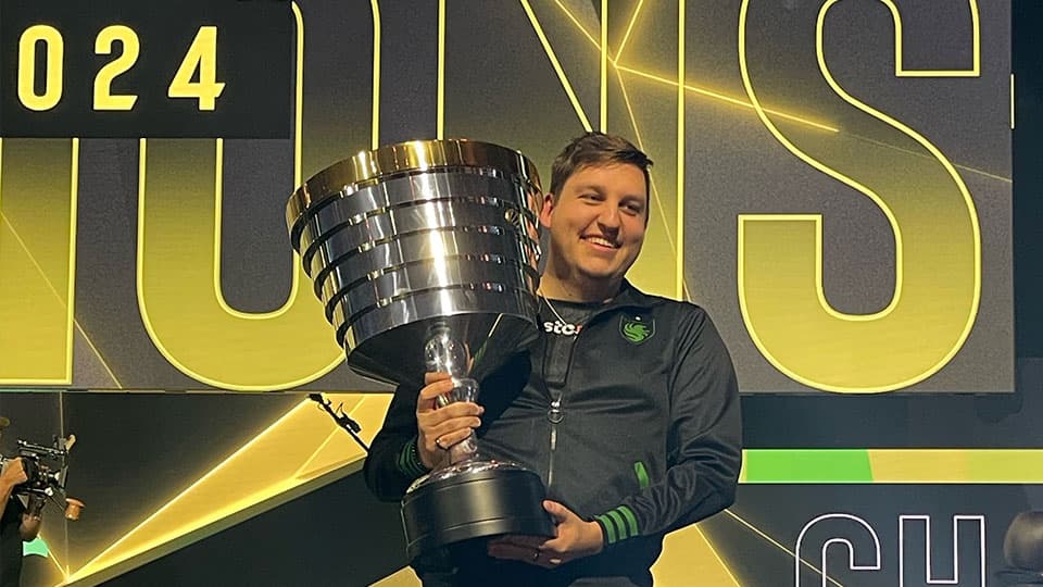 Alumnus Grant holding ESL One trophy on stage at Resorts World Arena Birmingham.