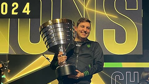 Alumnus Grant holding ESL One trophy on stage at Resorts World Arena Birmingham.