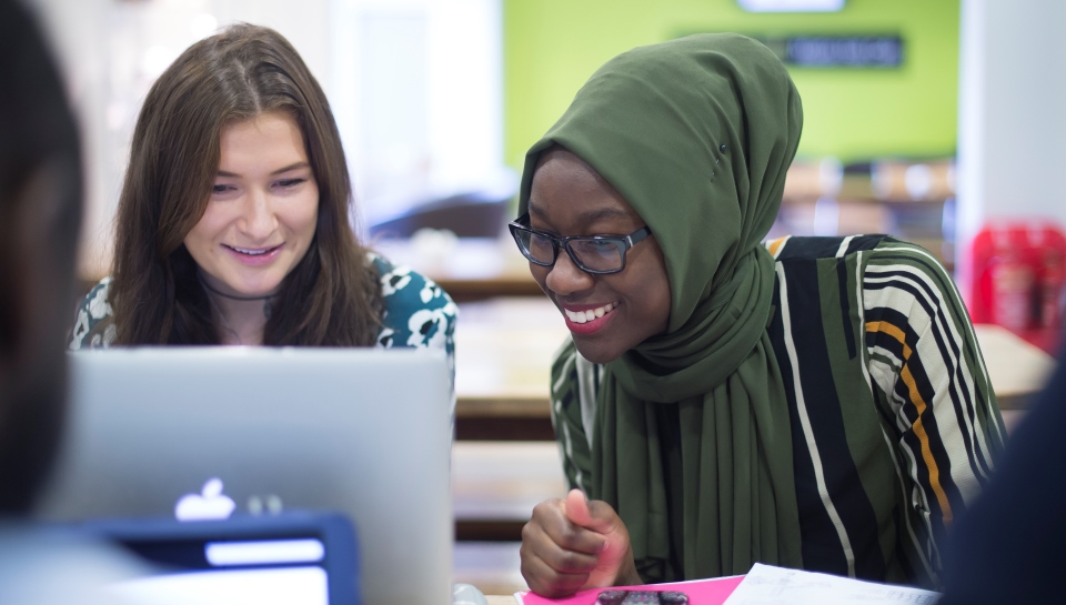 Two students look at a laptop