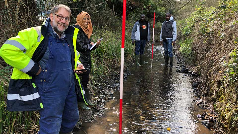 MSF and Loughborough University staff carrying out fieldwork into water sanitation in a stream. 