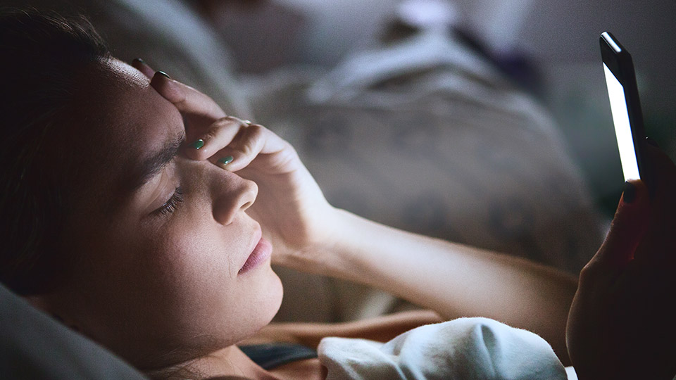 A teen on her phone in bed.