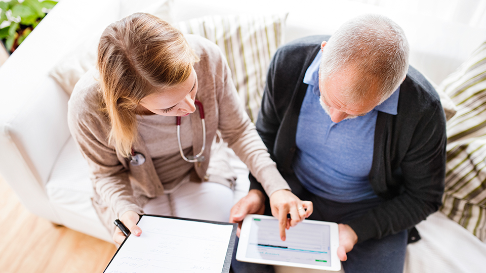 photo of doctor and patient sat down talking about information on a digital tablet