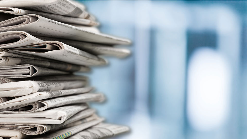 Pictured is a stack of newspapers.