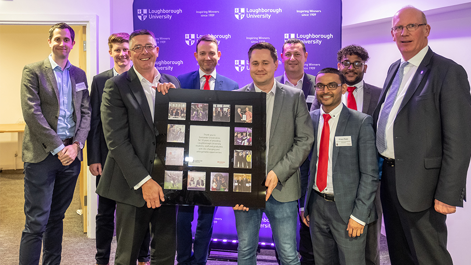 photo of Santander guests and University staff holding a plaque to acknowledge the 10-year partnership 