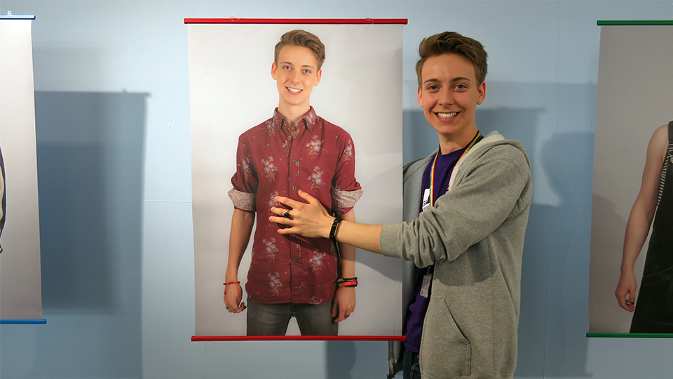 photo of Alex with his portrait at the LGBT+ exhibition