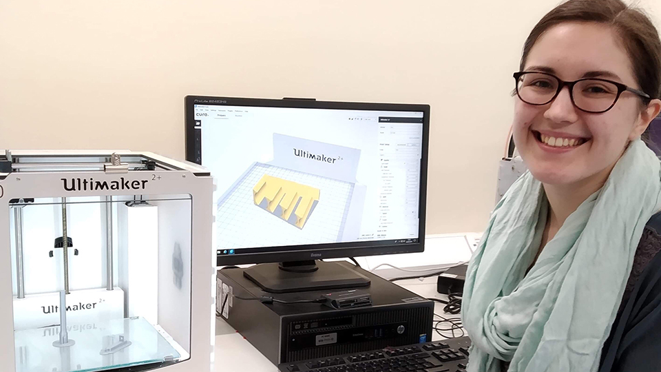 Photo of student Kate Walker sat at a desk with computer and 3D equipment 