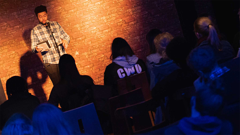 photo of spoken word artist performing to a crowd in Cognitos at LSU