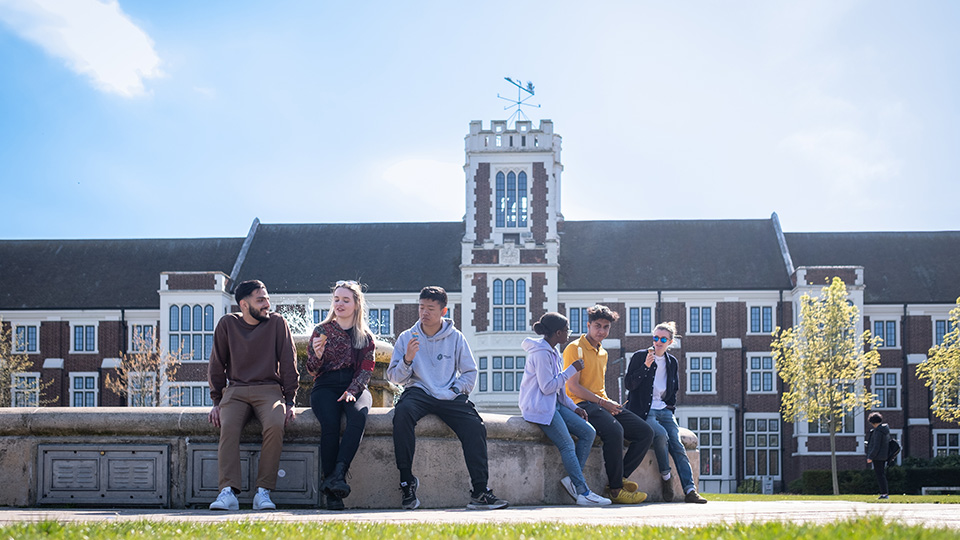 Photo of students sat on the fountain outside the Hazlerigg building