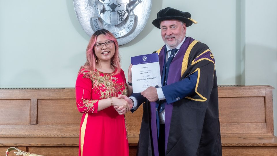 Huyen Le shaking hands with Professor Nick Jennings and holding a certificate.