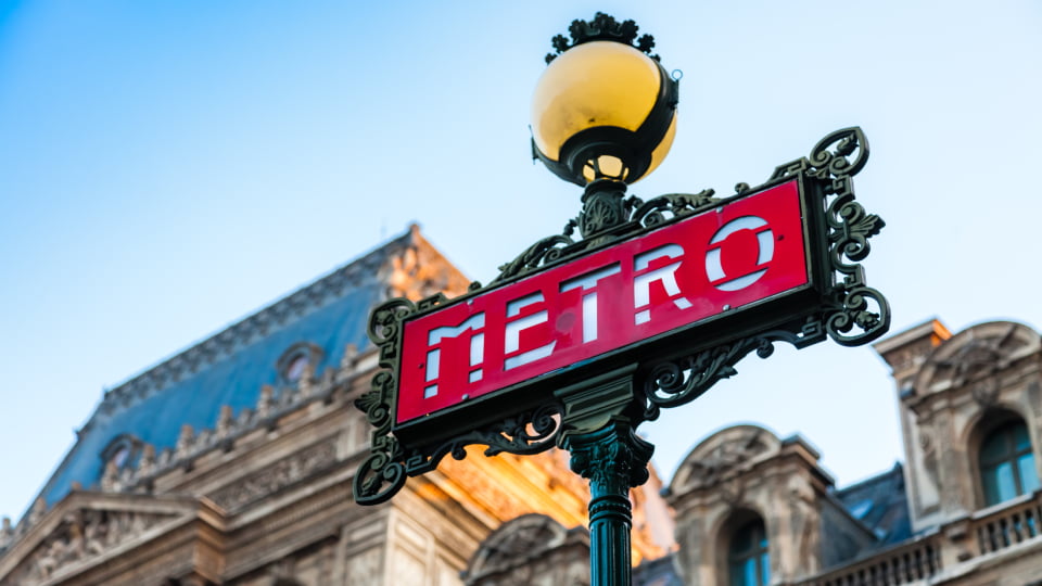 the paris metro sign with a blurred building in the background