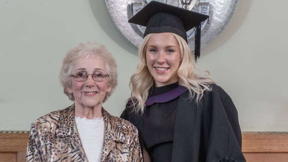 Photo of Sandra and Molly in her graduation outfit stood together