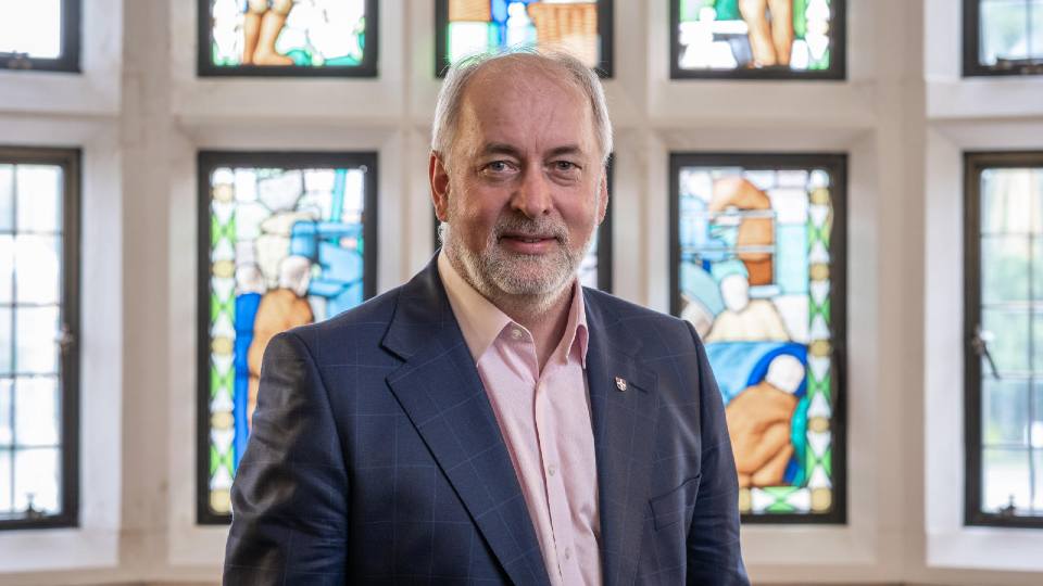 Professor Jennings stood in front of a stained glass window wearing a suit