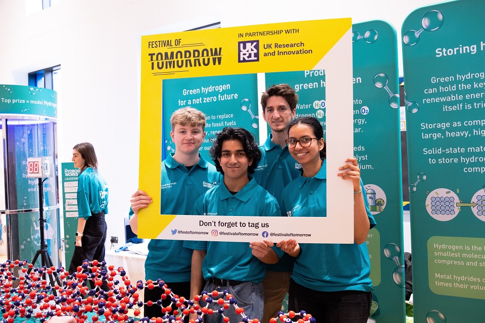 Four people are stood holding a large photo frame advertising the Fesitval of Tomorrow event