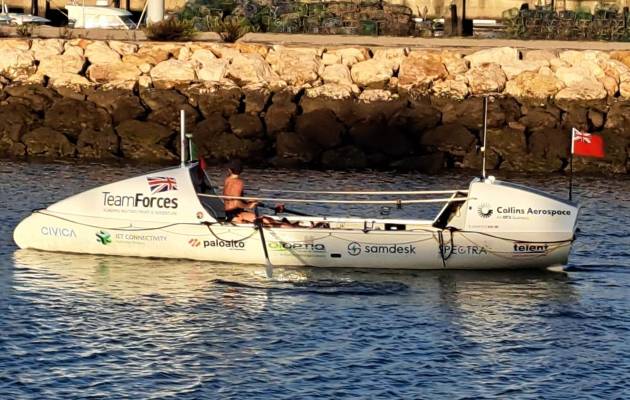 Zara sitting in a Team Forces branded rowing boat in the ocean.