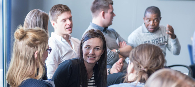 Group of students, some in discussion with each other, at an event for doctoral researchers