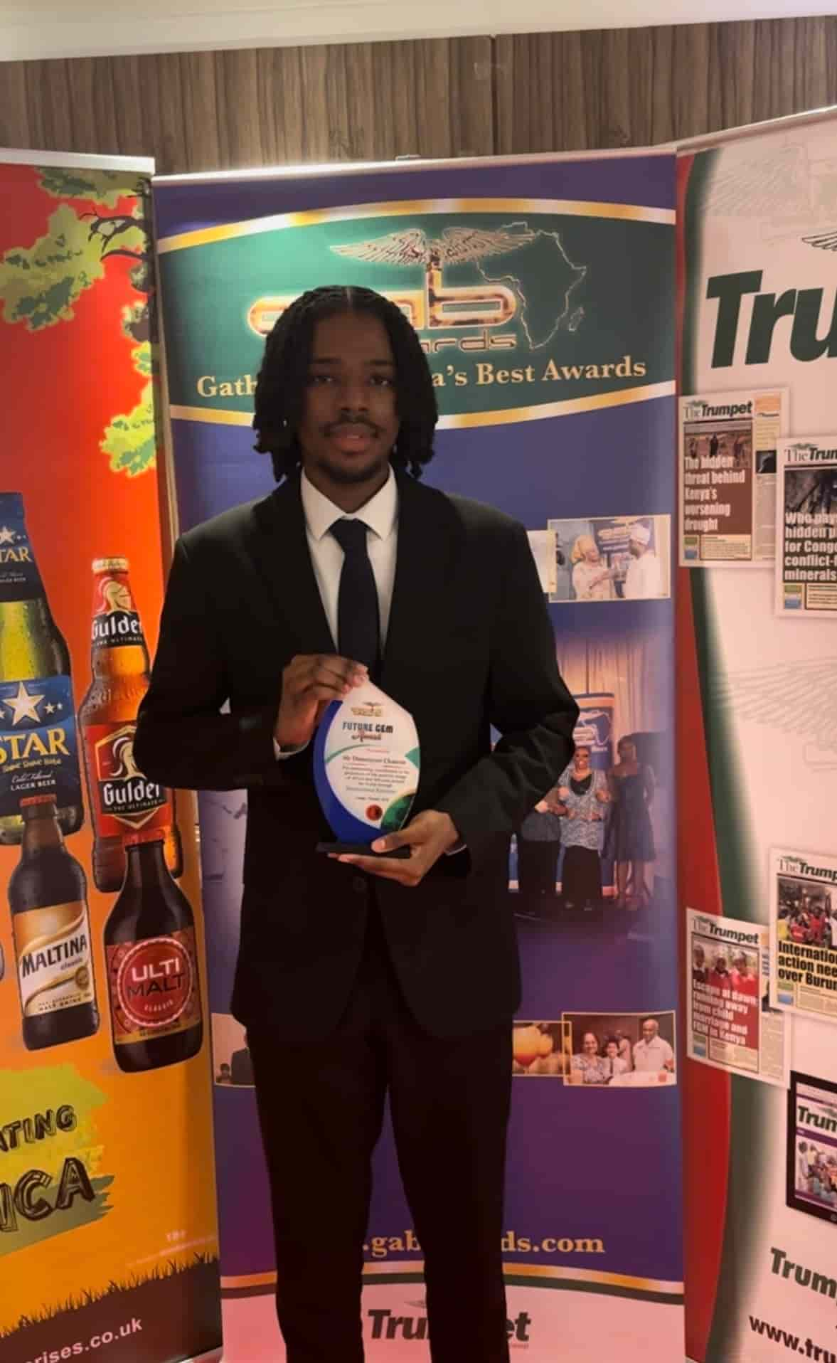 Toyosi Clement wearing a suit and holding an award.