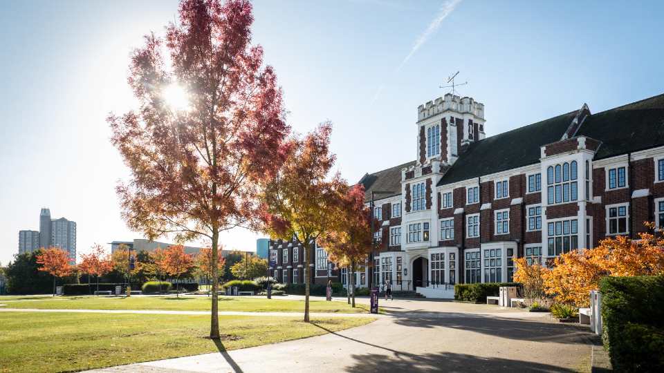 Hazlerigg building on Loughborough campus, sun is shining through the autumn trees.