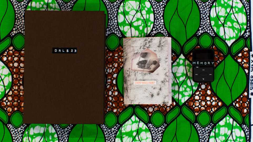 A green and brown patterned background with two books on top, one labelled 'Deep Recovery' and a small remote control labelled 'Memory'.