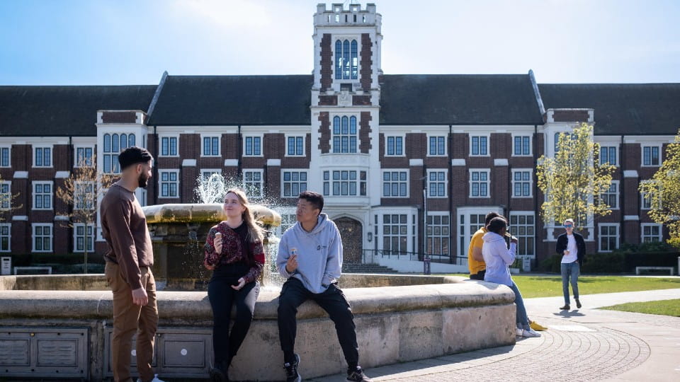 Three students at a fountain chatting and smiling