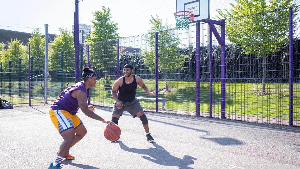 two men playing basketball outside at one of the ball courts on the University campus